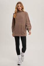 Model wearing mock neck tunic sweater paired with leggings