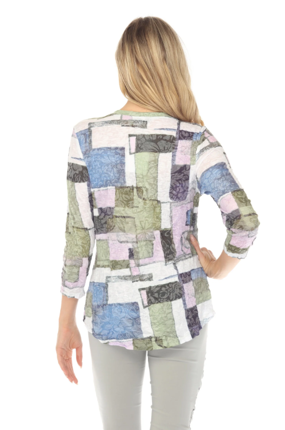Woman wearing a V-neck top with 3/4 sleeves, contrast stitching, and a curved hem. Made from lightweight burnout crinkle fabric, perfect for travel. In the pattern Meadow Mosaic.