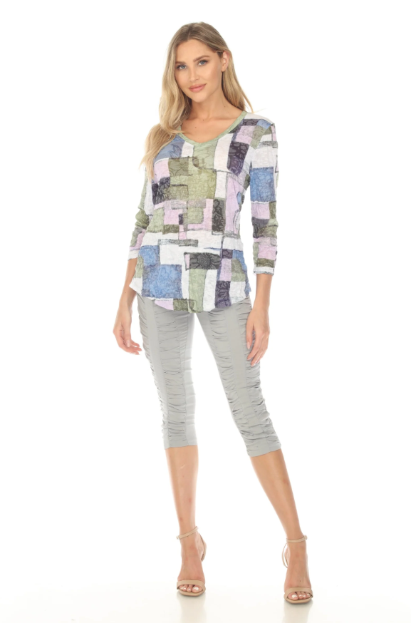 Woman wearing a V-neck top with 3/4 sleeves, contrast stitching, and a curved hem. Made from lightweight burnout crinkle fabric, perfect for travel. In the pattern Meadow Mosaic.
