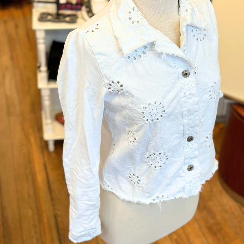 Femme Fatale Embroidered Eyelet Jacket – Women's cropped spring jacket with button front, eyelet embroidery, frayed edges, and soft stretch jersey sleeves and back. Stylish and versatile layering piece. In the color White.
