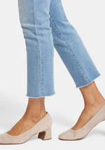 Close-up of frayed ankle hem and medium-light blue denim texture