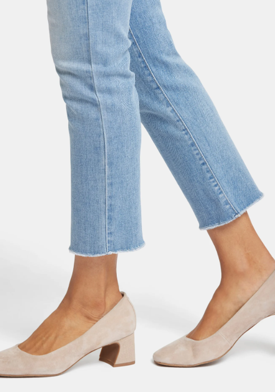 Close-up of frayed ankle hem and medium-light blue denim texture