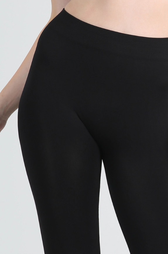 Full-length view of soft Nikibiki ankle leggings in the color black on model