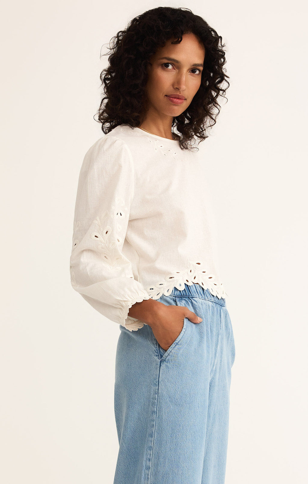 Model wearing the Ambirose Top – white cotton linen eyelet blouse with balloon sleeves and scalloped hem, perfect for spring and summer