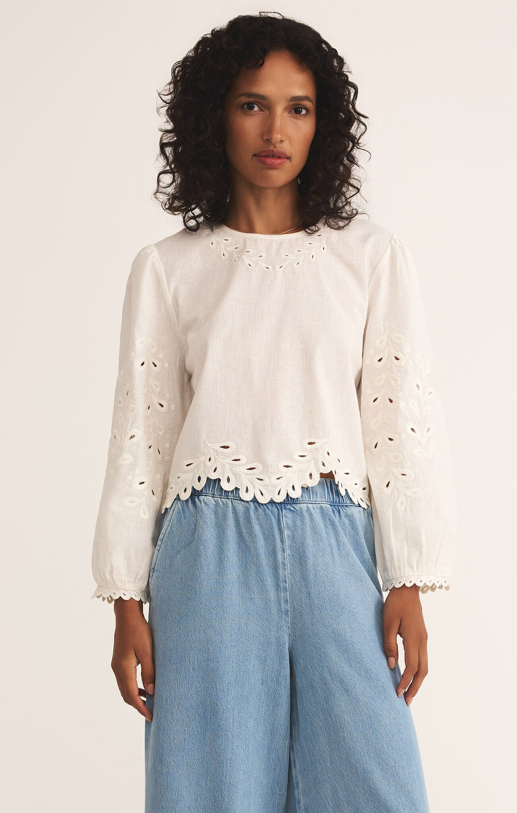 Model wearing the Ambirose Top – white cotton linen eyelet blouse with balloon sleeves and scalloped hem, perfect for spring and summer