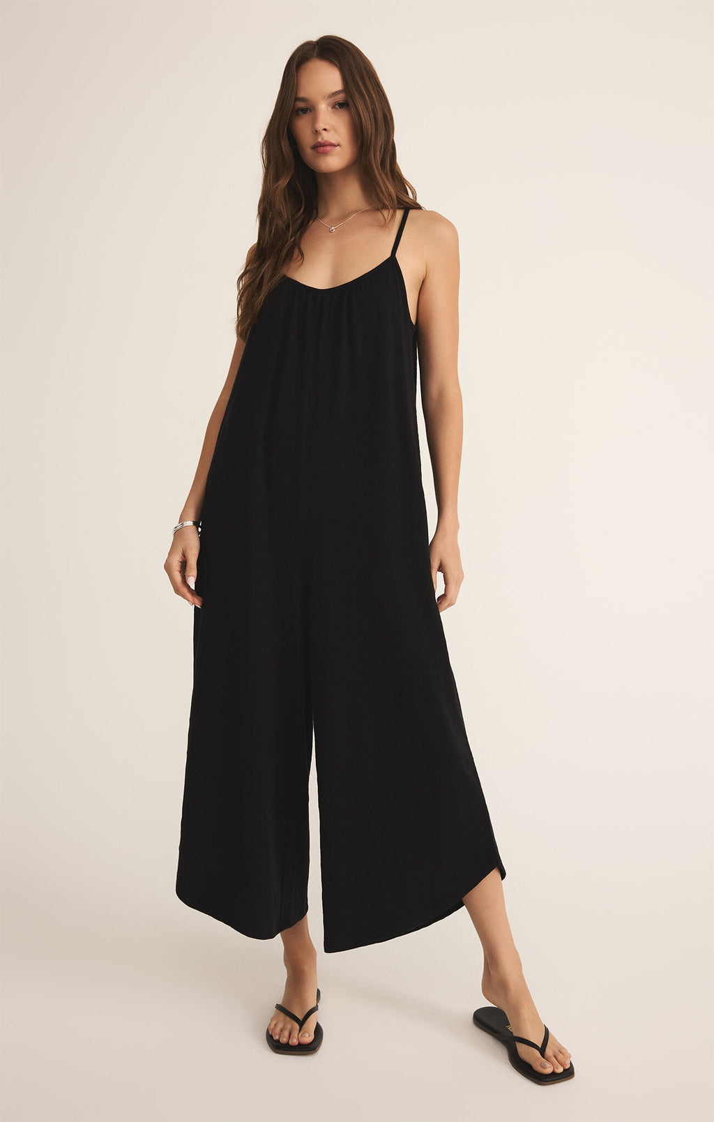 Full-length image of cropped Z Supply jumpsuit in Black styled with sandals