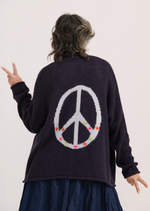 Woman wearing navy cardigan with embroidered peace sign and flower details on the back