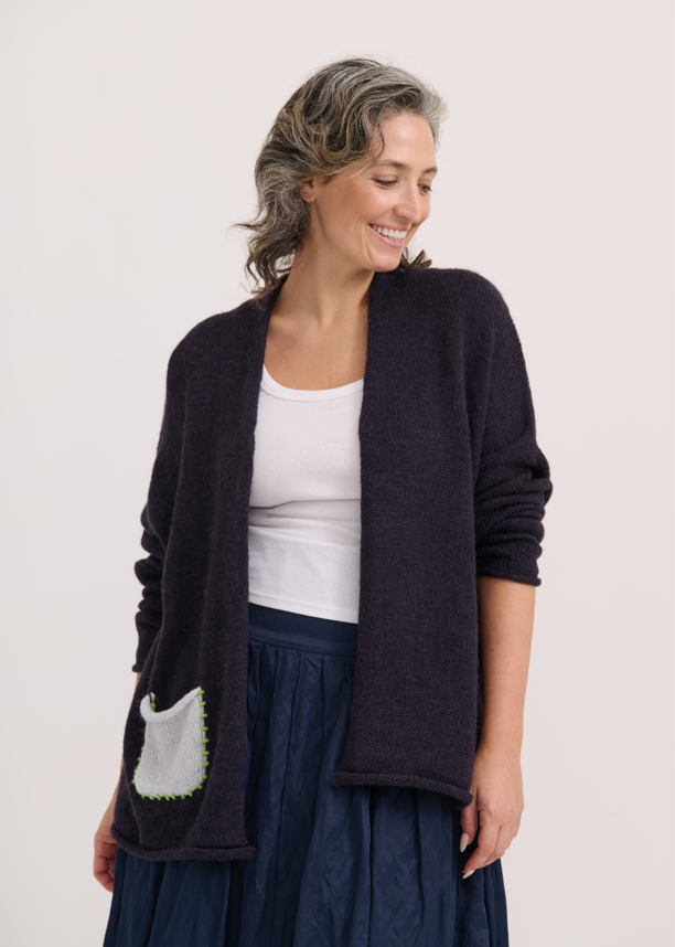 Woman wearing open-front navy cardigan with contrasting front pocket detail